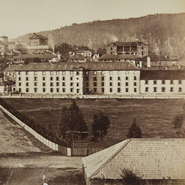 Historic photograph of a large multi-story barracks or institutional building complex with hills in the background.